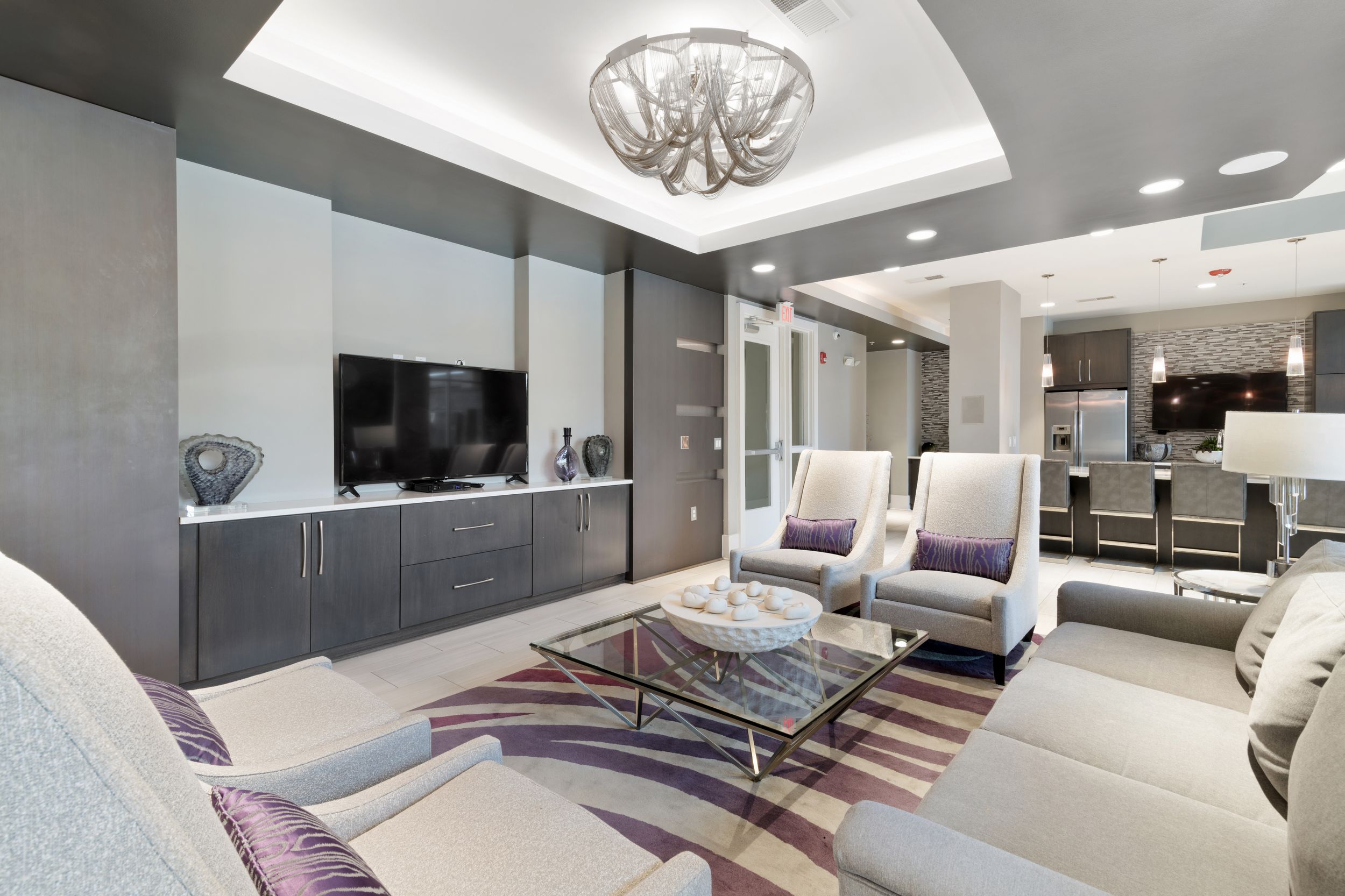 Clubhouse with modern furniture, a full-sized refrigerator, and seating areas with TVs at Lantower Weston Corners.
