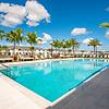 Resort-style swimming pool, palm trees, cabanas, lounge chairs, umbrellas