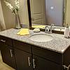 Bathroom sink with gray granite countertops and dark cabinetry