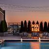 Swimming pool with seating and a LED sign that says "Pool Side" with view of city