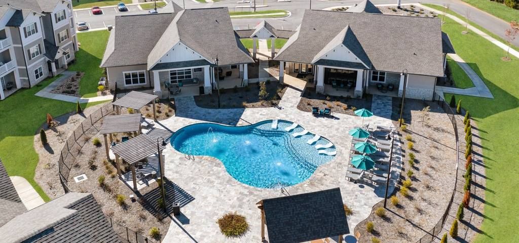 Aerial view of swimming pool with sundeck, seating, and cabanas
