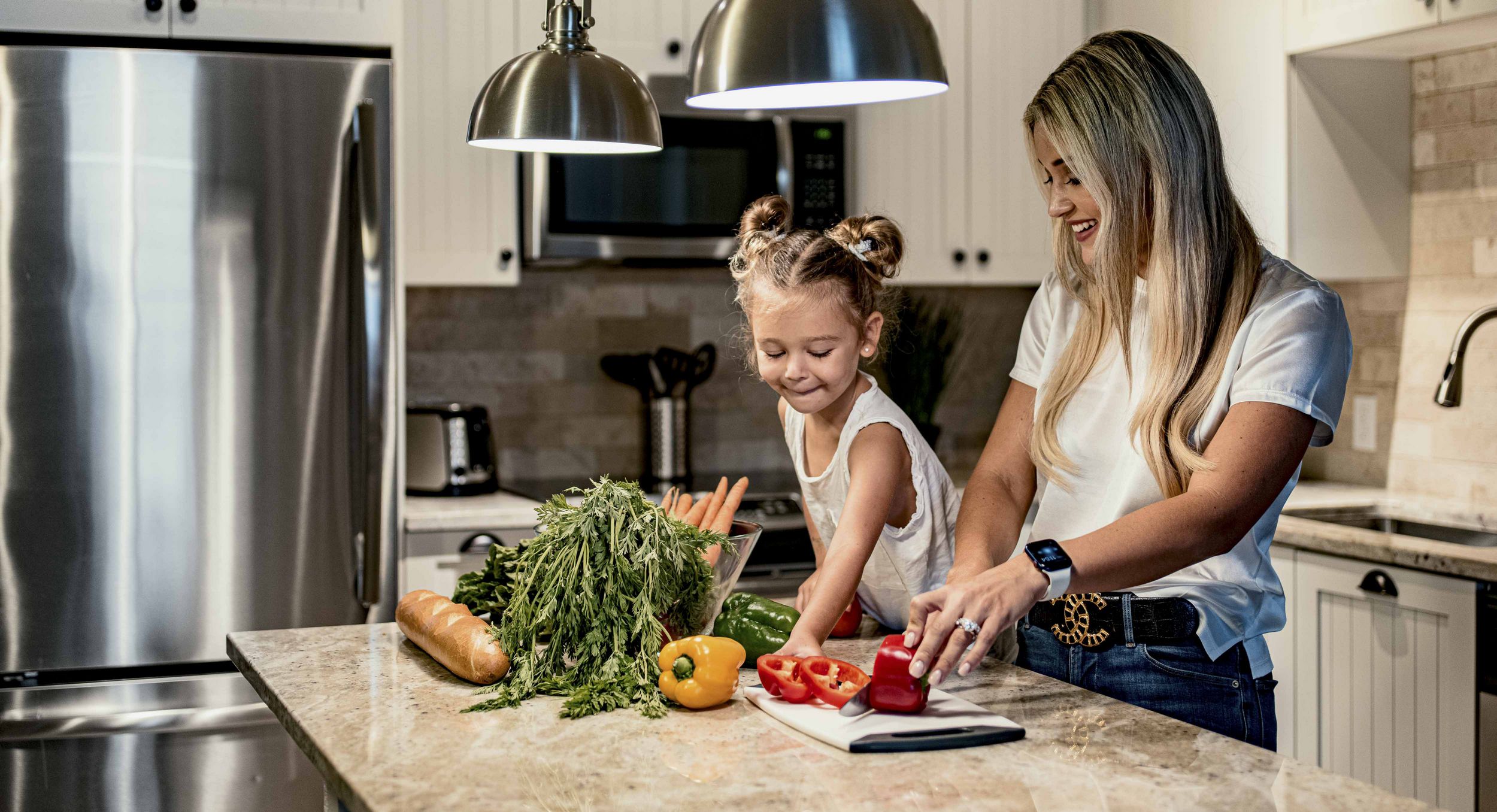 Woman and child cutting vegetables on kitchen island