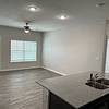 Kitchen island with view of unfurnished living area with hard flooring