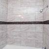 shower with a decorative band of dark tiles around the top