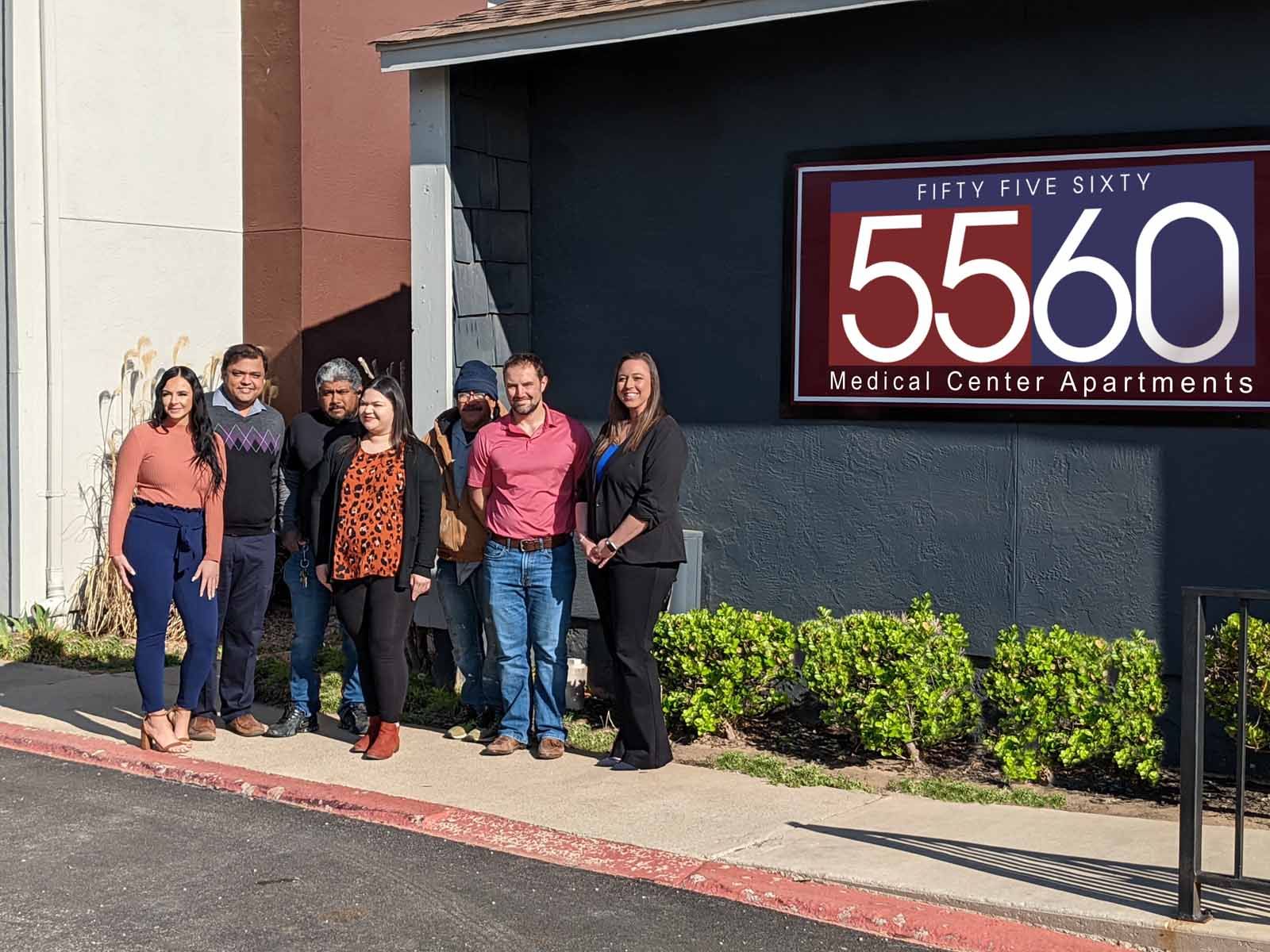 a group of people standing near the sign for 5560 Medical Center Apartments