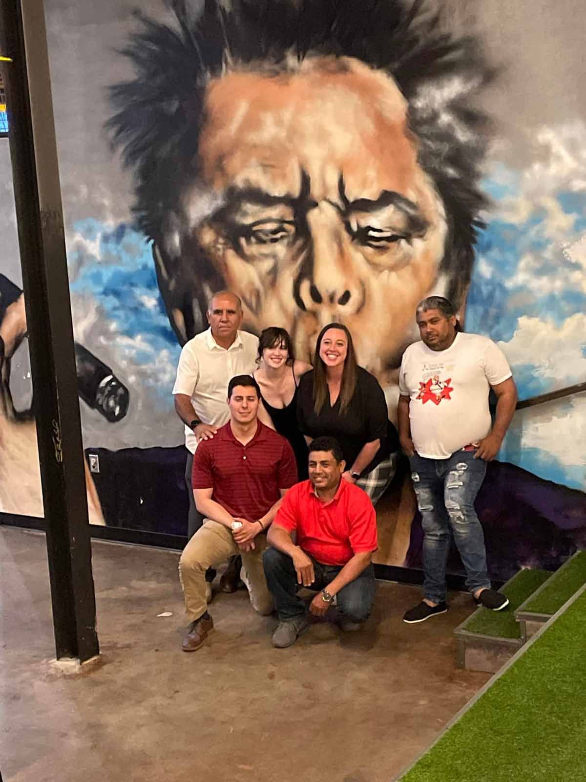 a group of people standing in front of a mural of a face with closed eyes