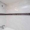 shower with a decorative band of dark tile around the top