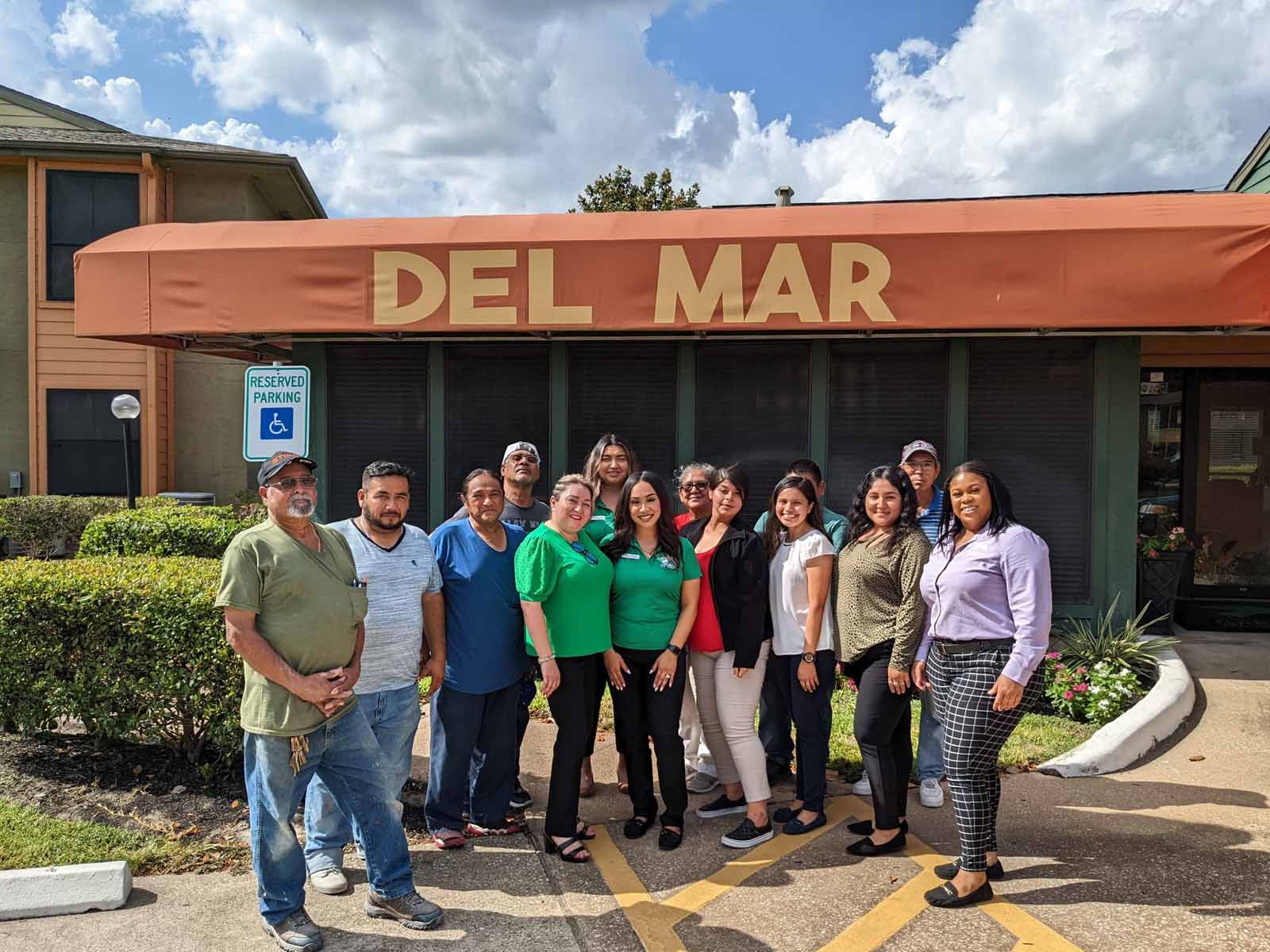 a group of people standing under the sign for Del Mar apartments
