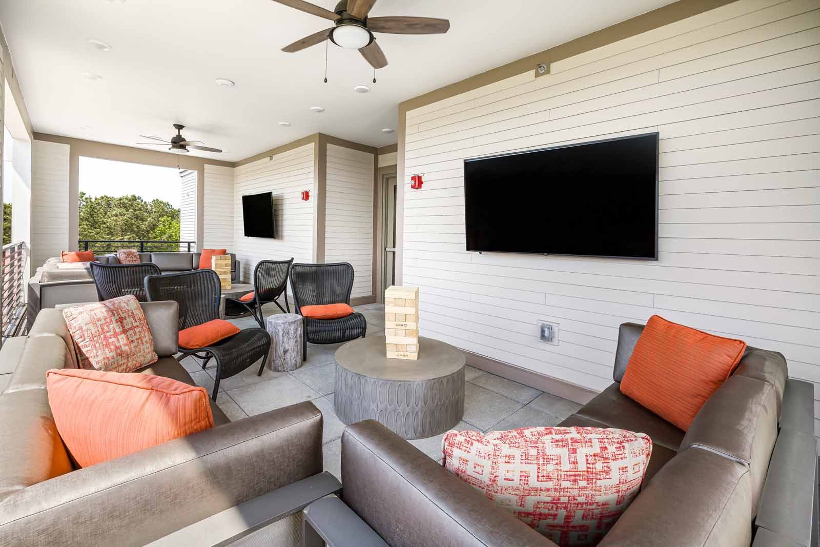 Outdoor lounge area with mounted tvs and fans
