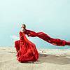 Woman in red dress dancing on sand