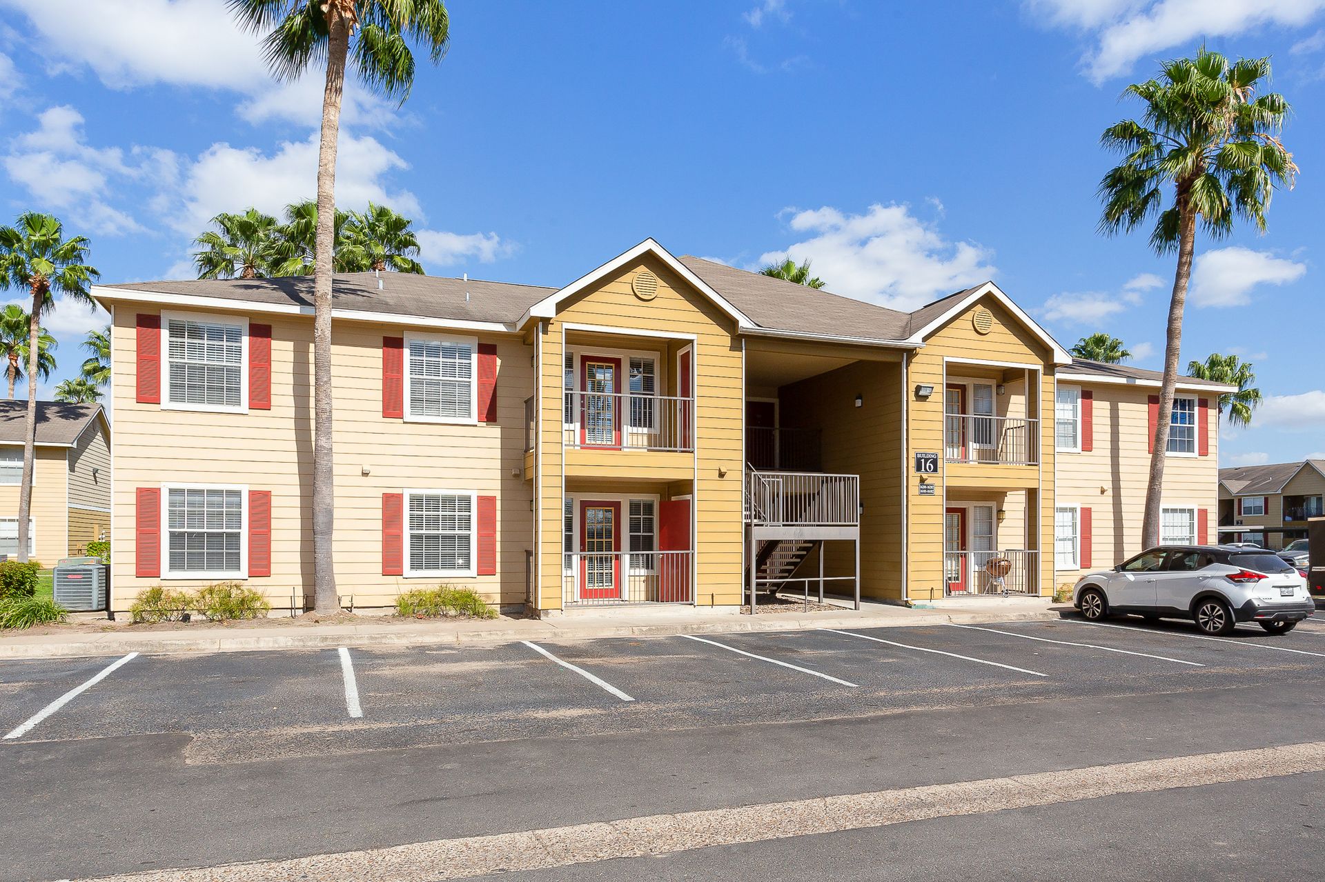 exterior of apartment building with parking and palm trees