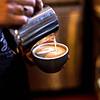 Person pouring cream into a coffee cup