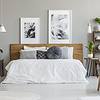 Bedroom with white bedding, pictures on the wall, lots of plants