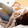 Woman laying on a sofa holding coffee in a mug