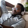 Man laying on couch at home listening to headphones
