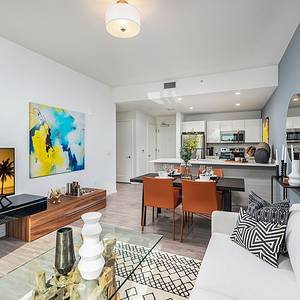 Apartment living area with couch, entertainment center, dining table, wall decorations and coffee table.