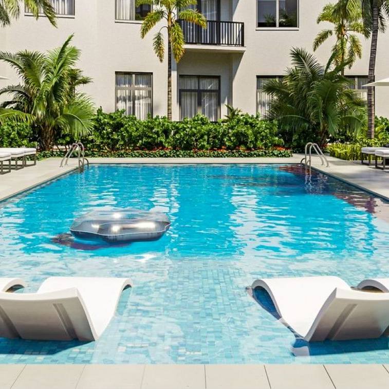 Pool with chaise lounges, palm trees and chair with apartment building in the background