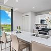 Quartz countertops with oversized kitchen islands kitchen bar area with three chairs and a view of large windows facing the laguna at Solé Mia Rentals in North Miami, Florida