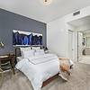 Contemporary Designs Apartment bedroom, with bed, end table, desk, art work on walls, and view into the bathroom at Solé Mia Rentals in North Miami, Florida