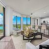 Floor-to-ceiling windows Apartment living area with couch, chairs, coffee table, large windows with view to laguna at Solé Mia Rentals in North Miami, Florida