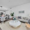 Luxury Finishes Apartment living area with area rug, couch, chair, dining area, lamps and wall hangings at Solé Mia Rentals in North Miami, Florida
